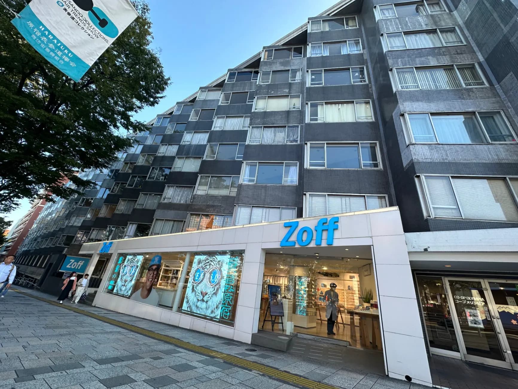 現代的な外観のZoffメガネ店舗、明るい看板とディスプレイウィンドウ、通行人が歩く歩道