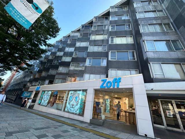 現代的な外観のZoffメガネ店舗、明るい看板とディスプレイウィンドウ、通行人が歩く歩道