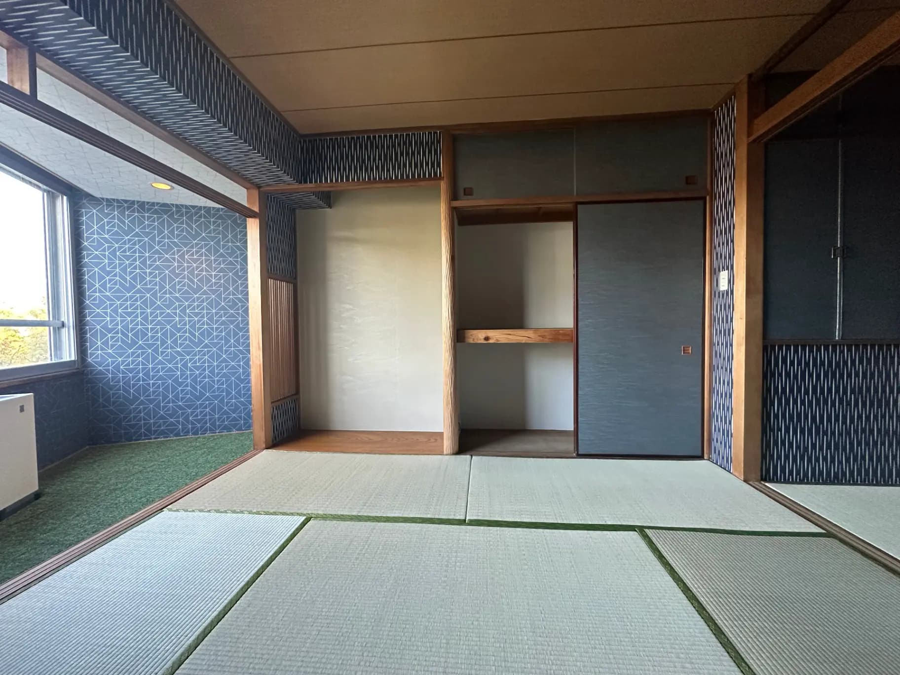 伝統的な日本式の和室、畳の床と青い壁紙、木製の建具とシンプルなデザインのインテリア