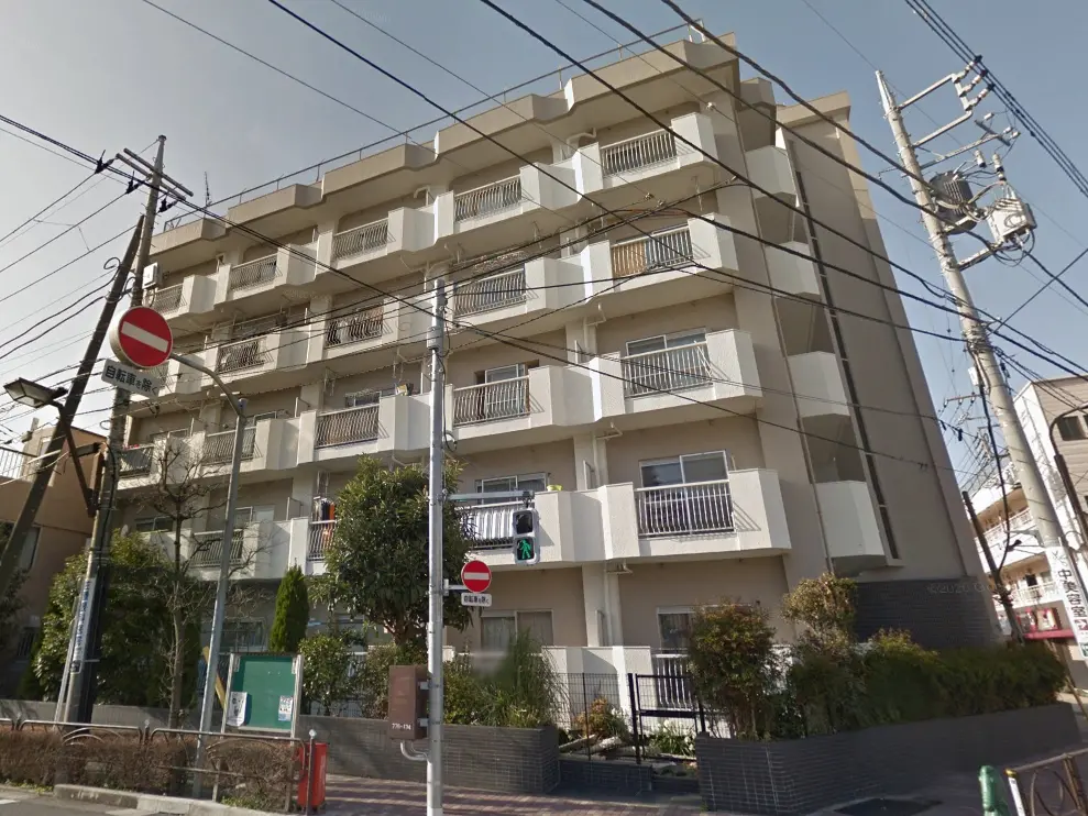 - 街中にあるモダンなマンションの外観、バルコニー付きのユニット、近くには交通信号や街路樹が見える風景