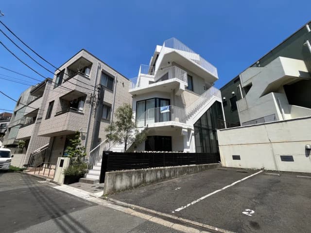 - 都会的な外観のマンション、階段やバルコニーが特徴的な建物、青空と街並みの美しい景色