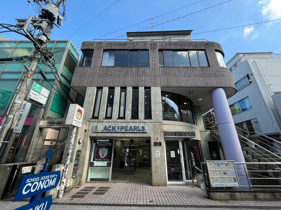 原宿にあるモダンな建物の外観、ショップとサロンの看板、都会的な電柱と透明な青空