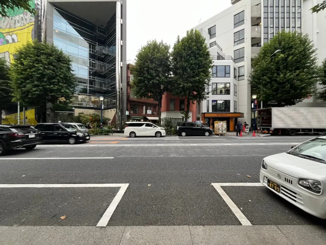 都市の街並み、交通量の多い道路、背景に現代建築と樹木