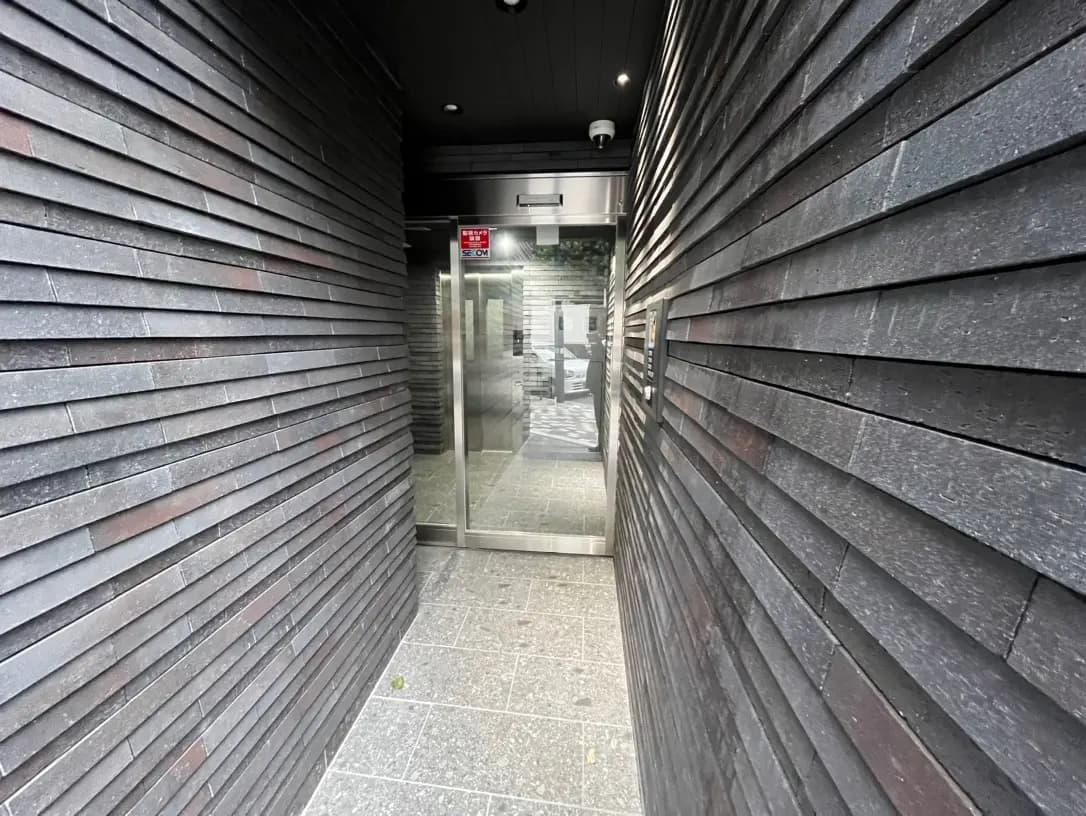 暗めの木材で覆われた通路とガラス扉、モダンな建築デザインの入り口