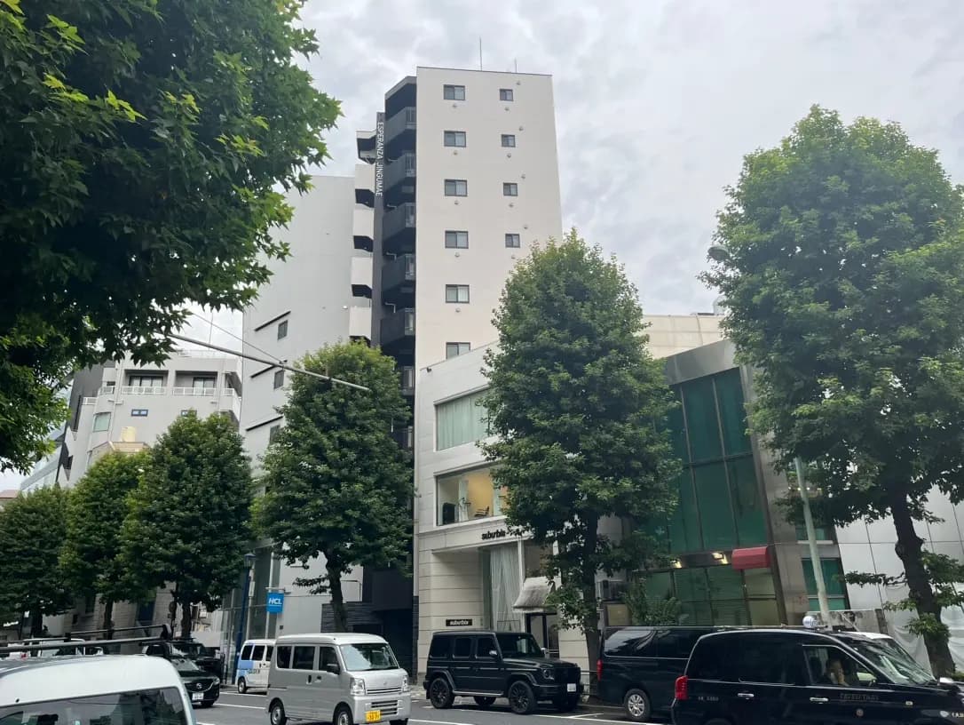 現代的な建築様式の都市部のマンションとオフィスビル、緑豊かな木々と路上駐車の車