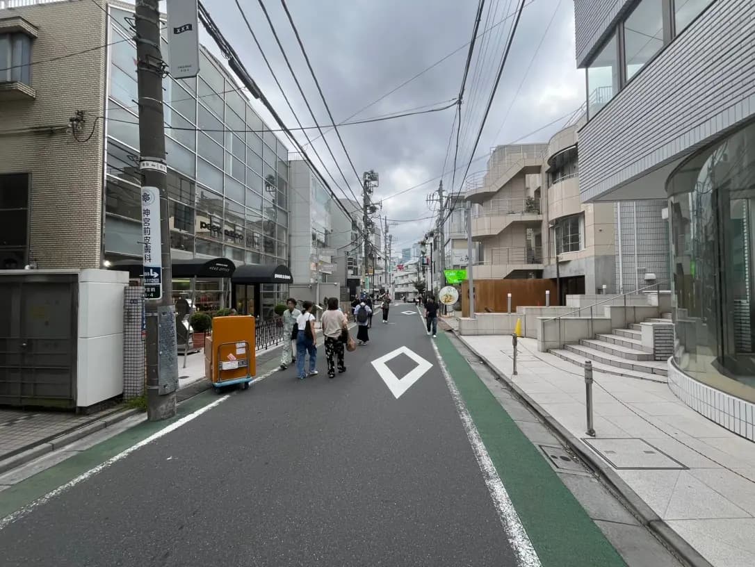 日本の都市部にある緑の自転車レーンが特徴的な街並み、歩行者や商業施設が見える風景