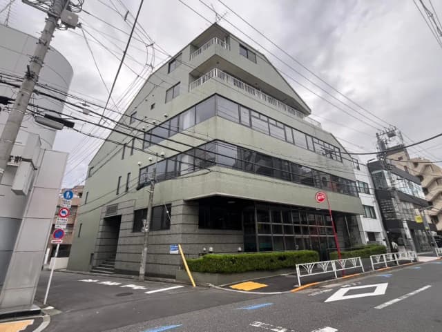 現代的な建築スタイルのオフィスビル、曇天の下で電線が交差する市街地の景観
