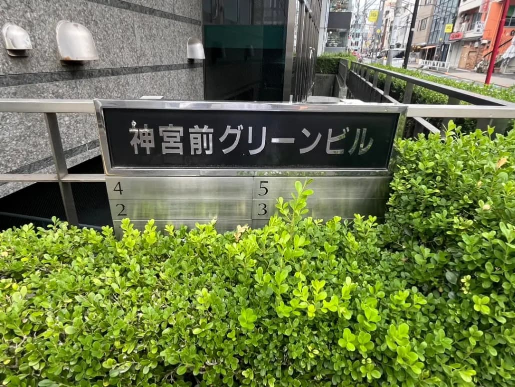 都会的な景観に囲まれた植栽とモダンな建物の看板、「福寿クリーンビル」の文字が特徴的なエントランス