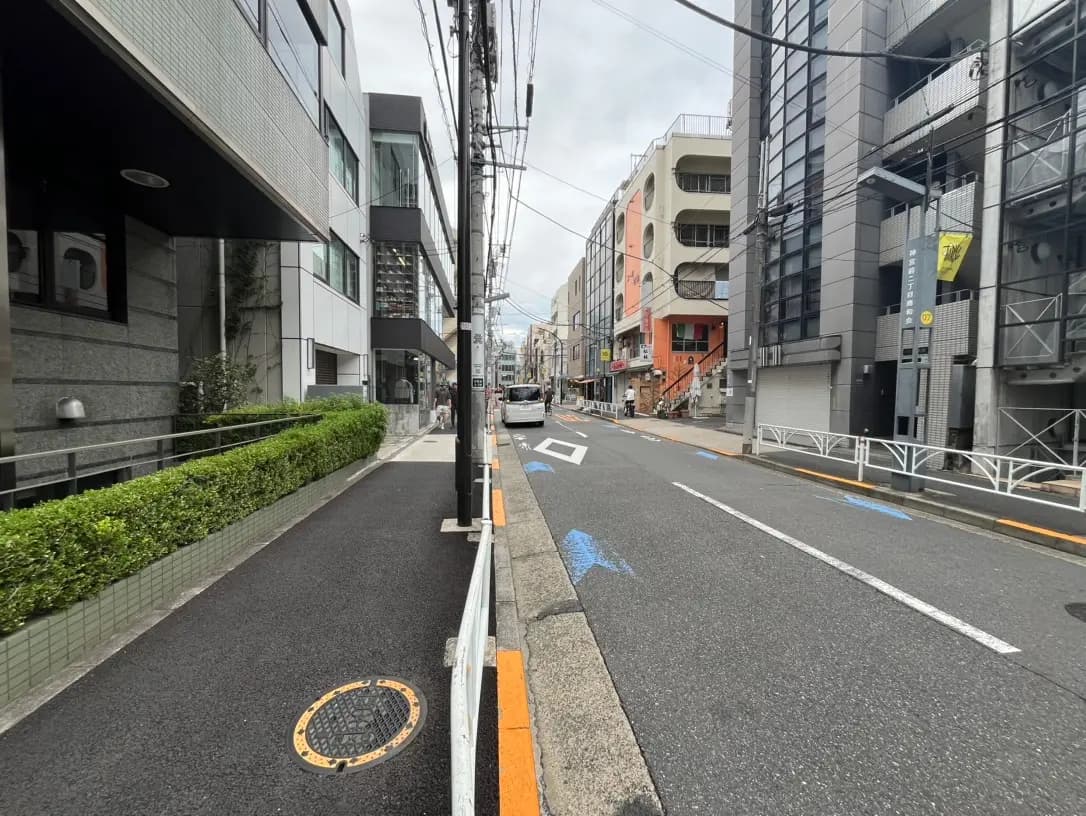 現代的な建築が並ぶ都市の通り、歩道と電柱、くもり空の下の静かな風景