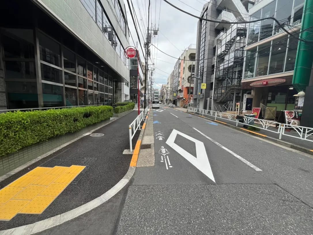 都市の道路と歩道、交差点近くにある自転車レーンマークと周辺の建物