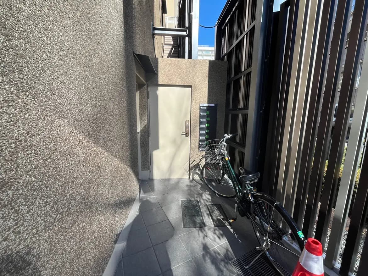 日差しが降り注ぐマンションのエントランス、自転車が置かれた都市の住居の玄関