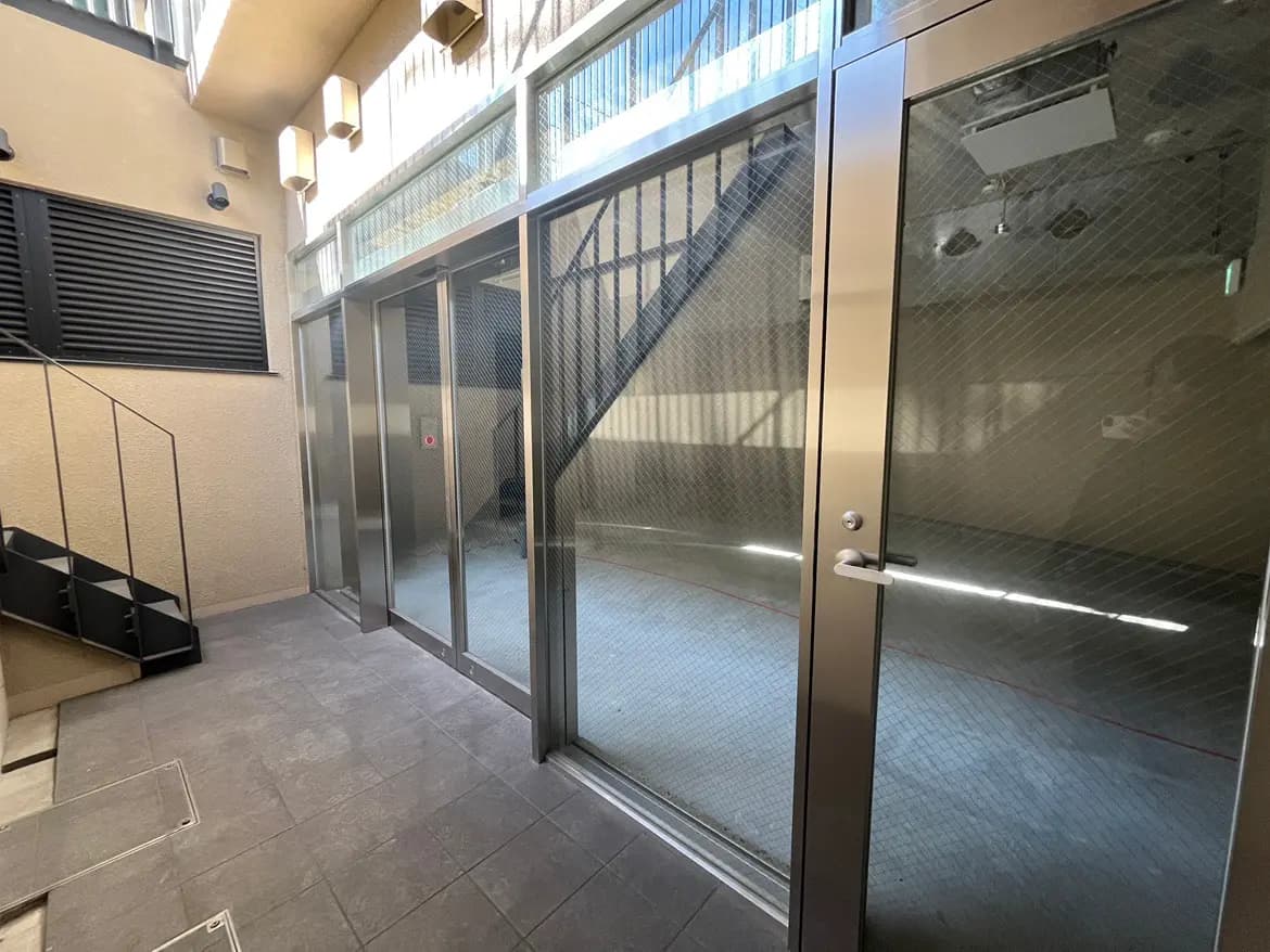 モダンな建物のエントランス、ガラス扉、階段、自然光が差し込む清潔感のある空間