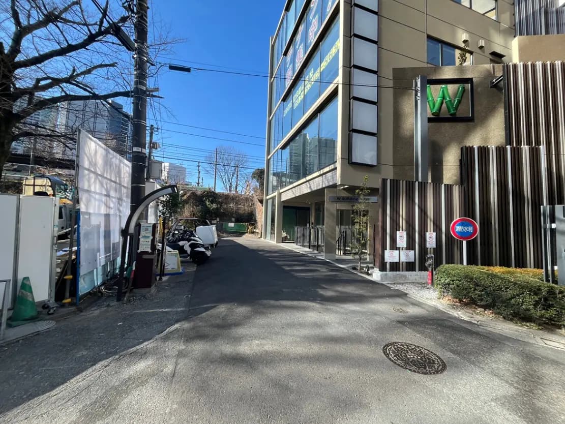 都市の日当たりの良い道路と現代的な建物、入口にある緑色のホテルの看板