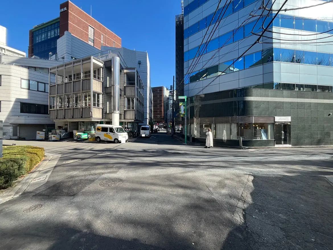 晴れた日の都市風景、ビルや店舗が立ち並ぶ交差点、歩行者、クリアな青空