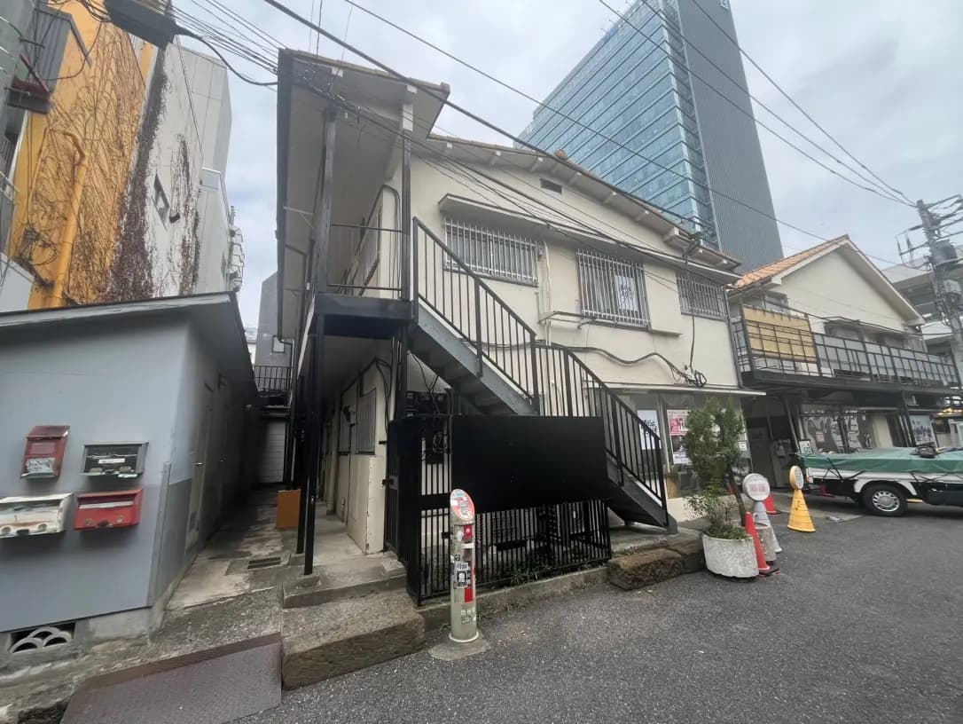 都市の狭い道にある古いアパートとモダンなガラスビル、電線が交差する風景