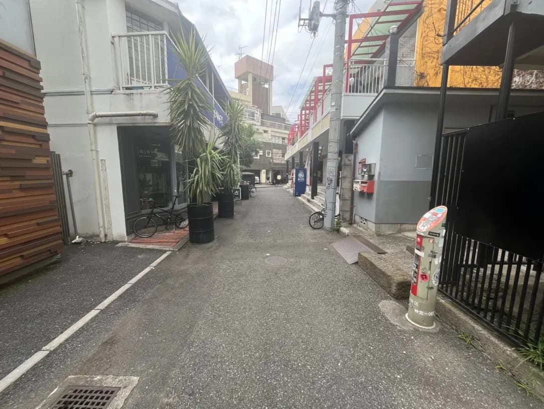 日本の都市の狭い路地、自転車と植物がある店舗の外観、都会的な生活感が漂う風景