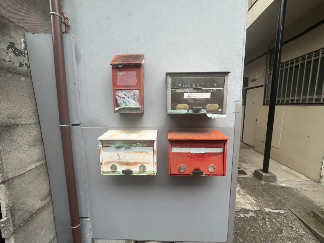 建物の壁に取り付けられた色あせた郵便受け、都市の生活感が漂う外観