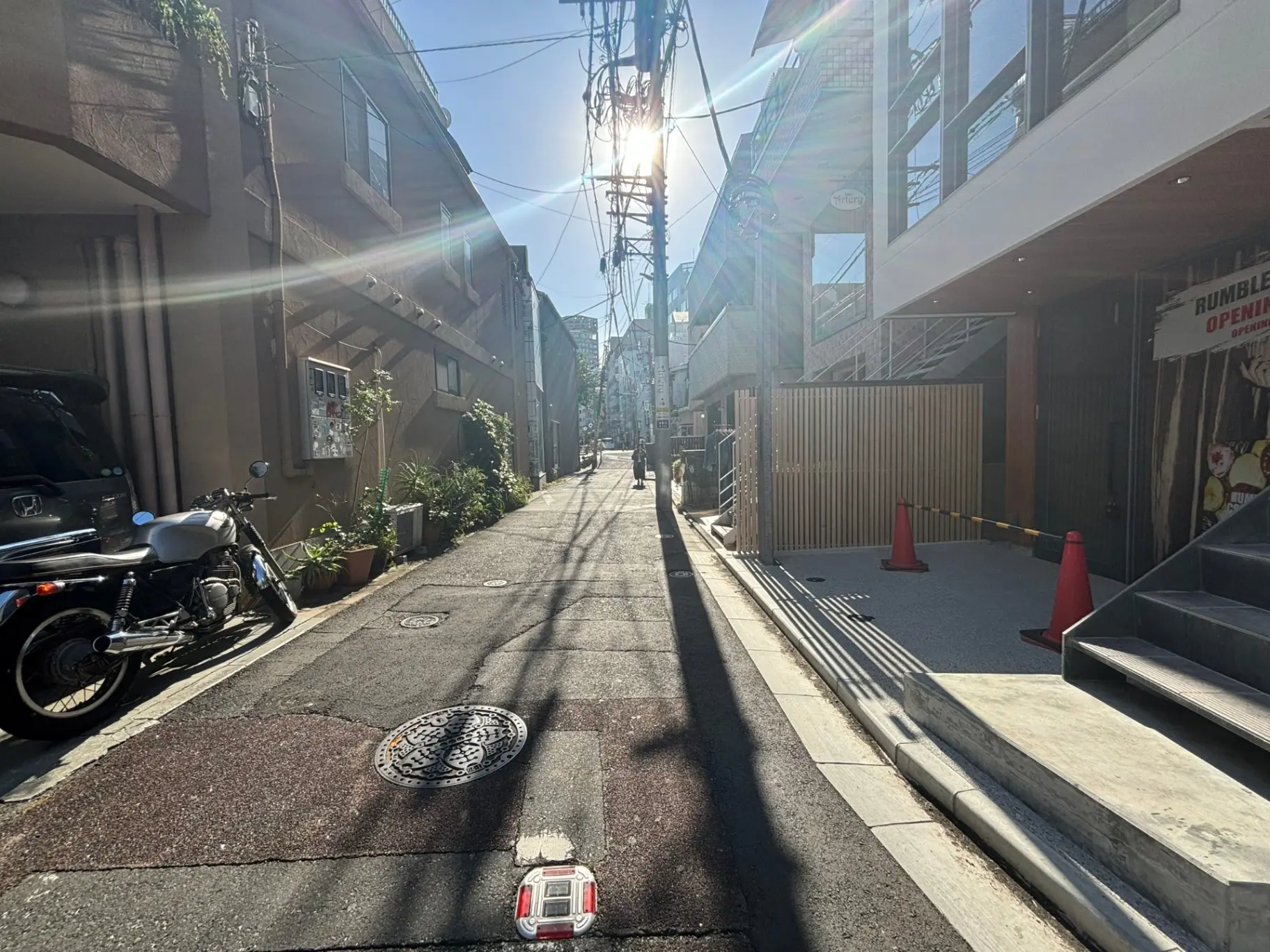 朝の光が差し込む狭い日本の路地、バイクが停まっている風景