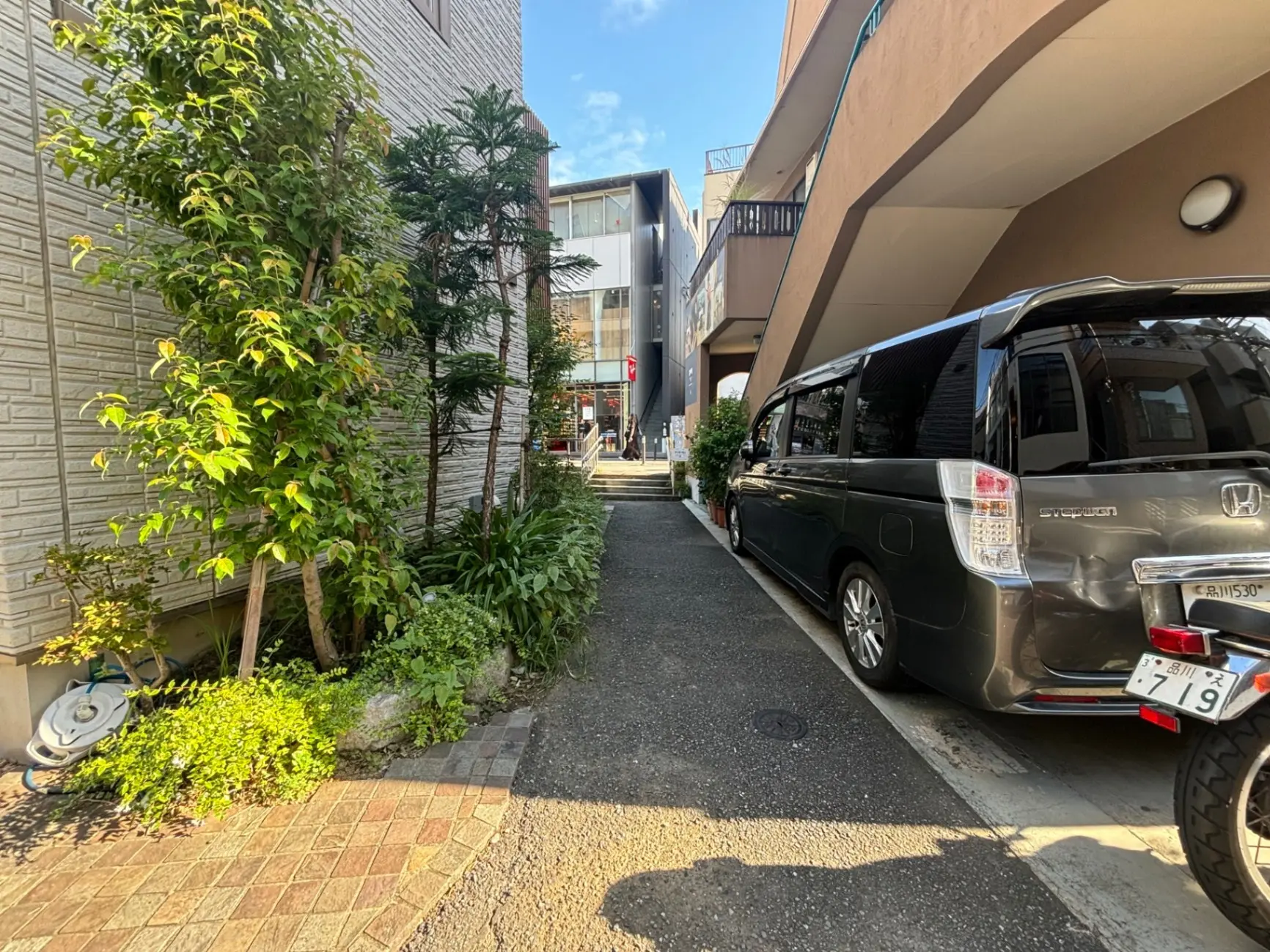 日本の住宅街の風景、緑豊かな植栽と駐車しているミニバン、青空と都市環境