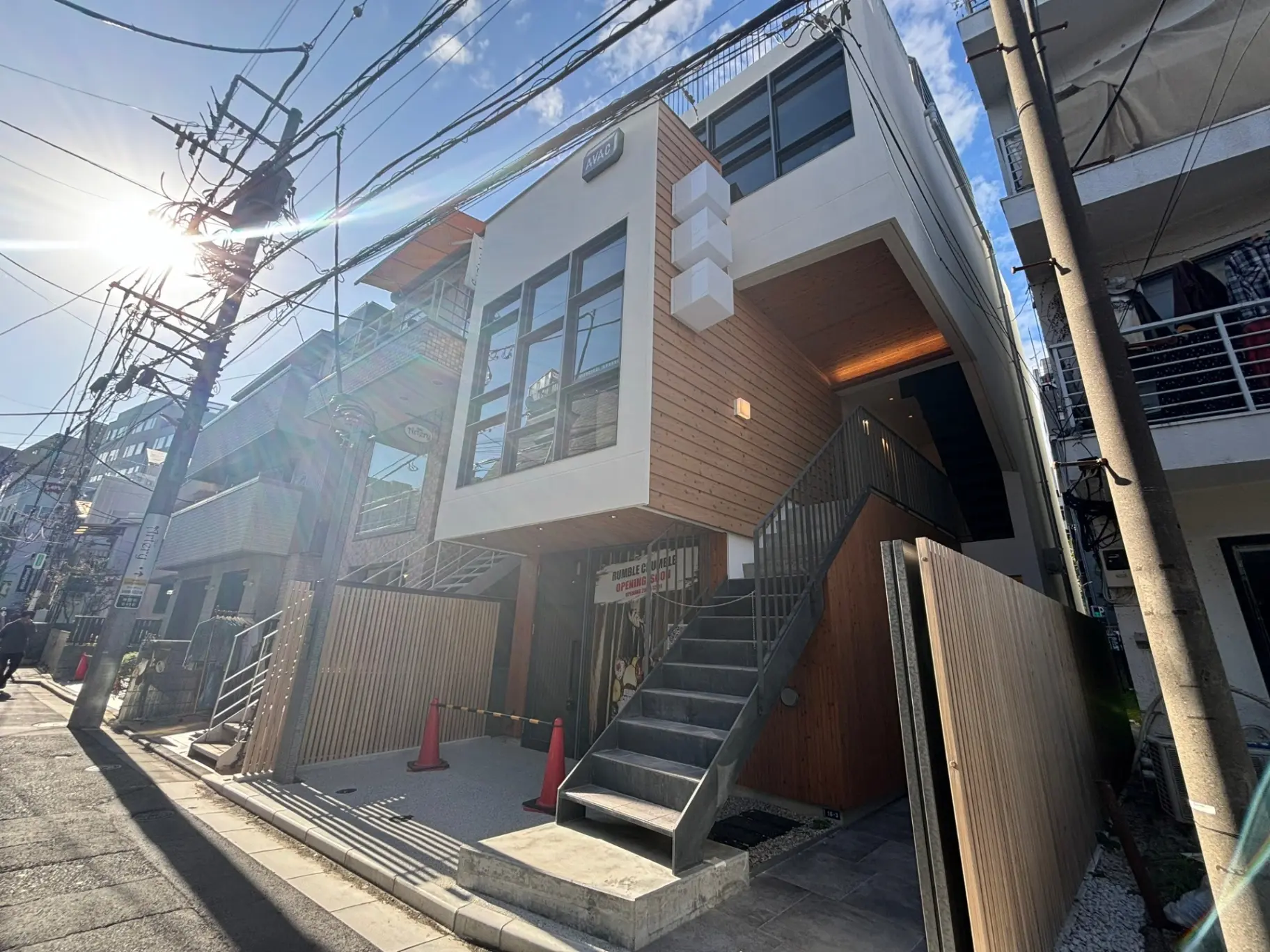 モダンな外観の店舗と住宅が融合した建物、都市の電線と歩道、晴天の日差し
