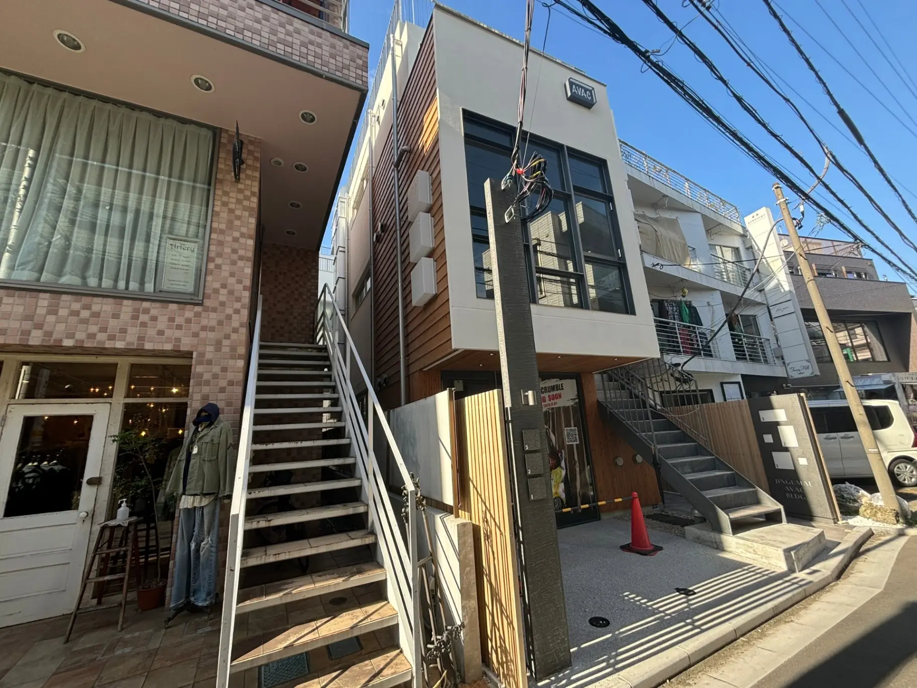 現代的な外観の店舗と住宅が混在する街並み、青空の下に人が歩いているシーン