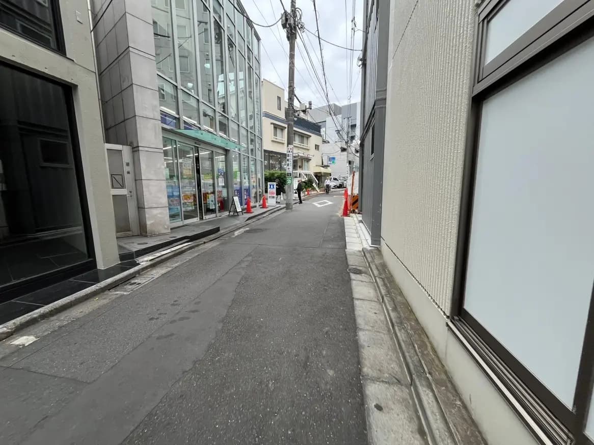 都会の狭い道路と歩道、曇り空の下の現代的な建物のファサード
