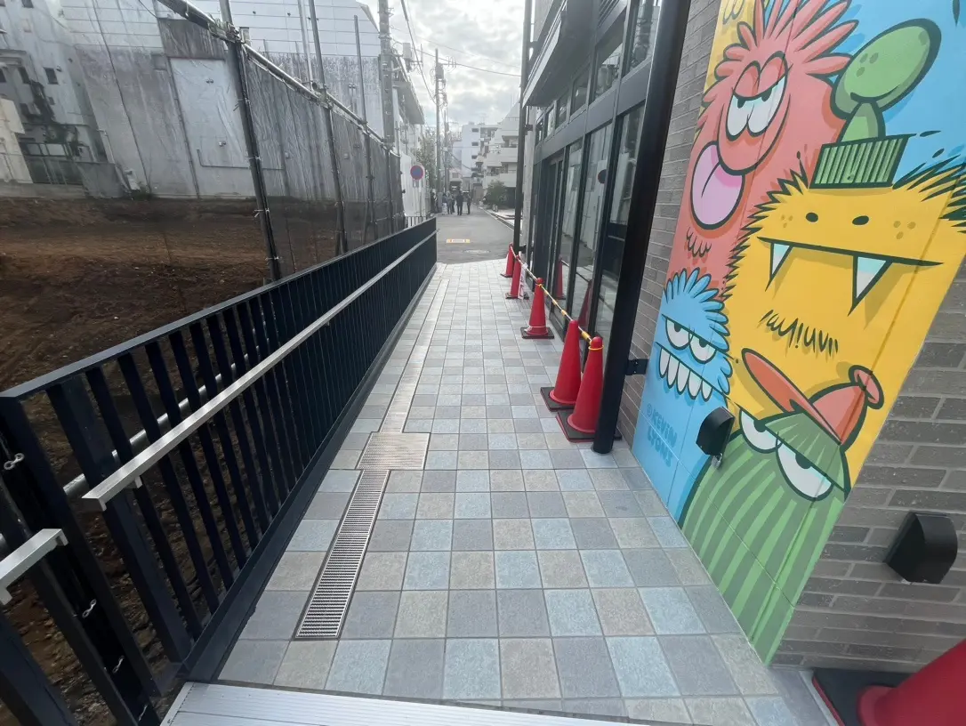カラフルなキャラクターが描かれた壁画と歩道、都市背景の建築現場の横 Gharienai