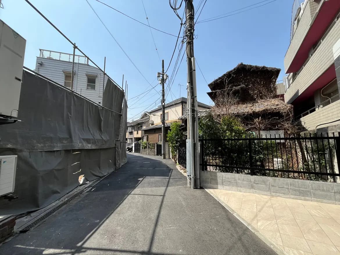 日本の住宅街の風景、青空の下の電線と住宅、工事現場と茅葺屋根の伝統的な家
