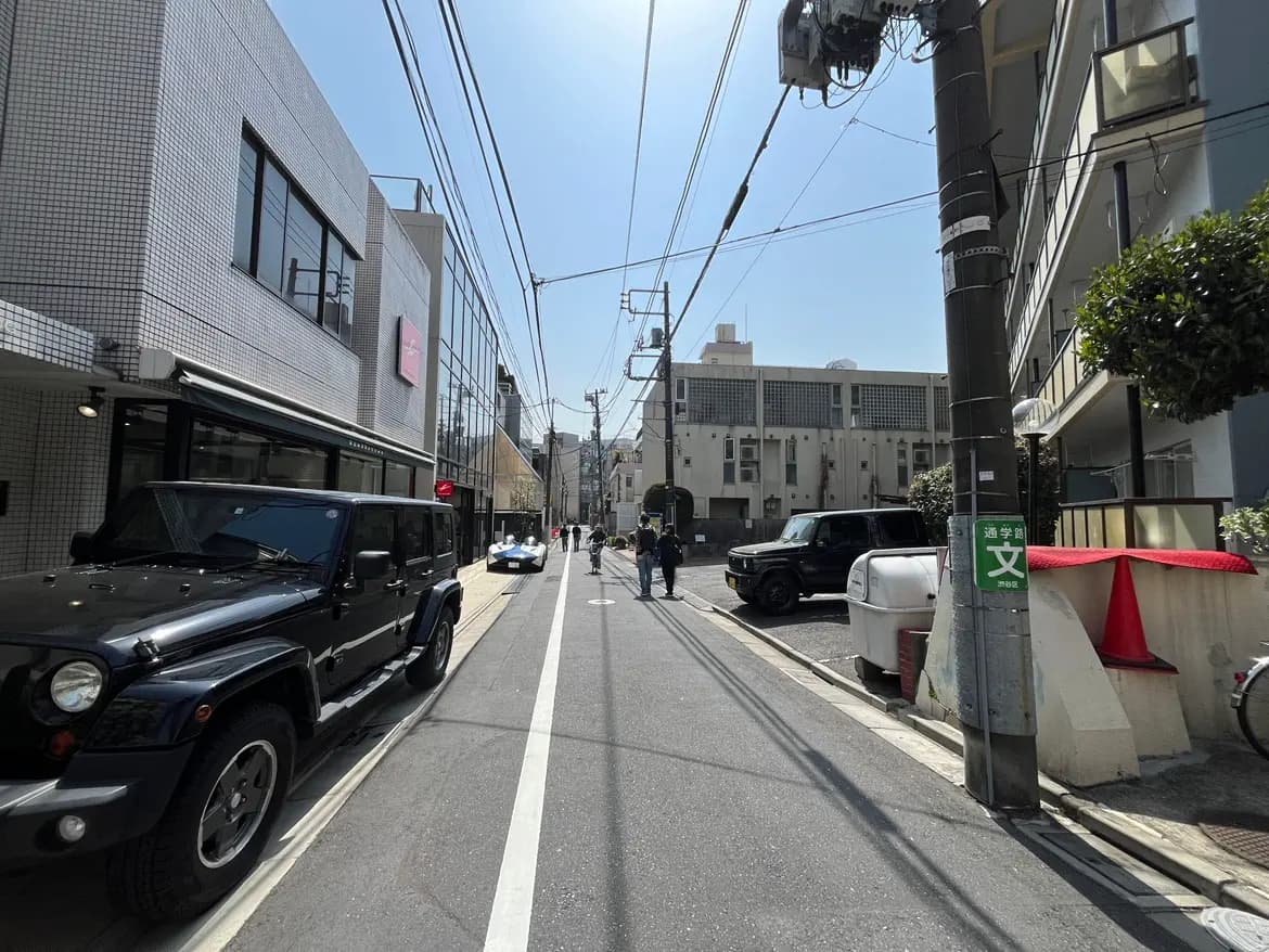 晴れた日の都市の通り、駐車している車と歩行者、架空電線と建物