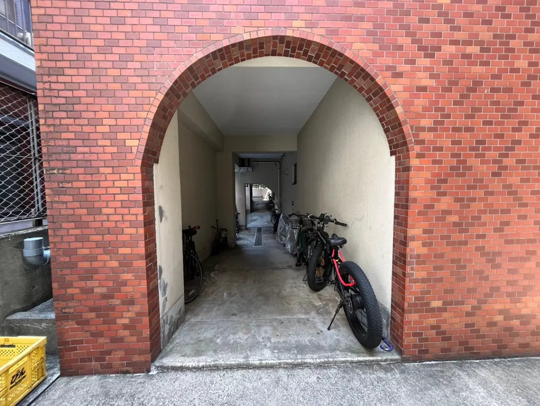 レンガ造りのアーチ型入口と自転車駐輪スペースがある建物外観
