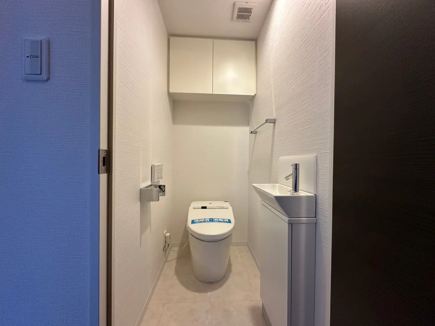 シンプルなデザインのトイレと洗面台、白い壁と青いドア、モダンな室内装飾