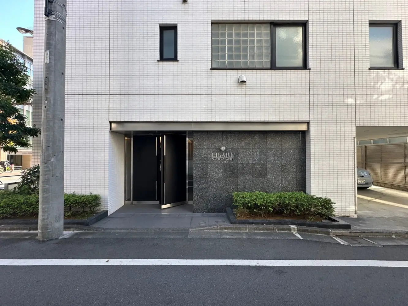 モダンなビルの入り口デザイン、グレーの外壁とタイル張り、清潔感のある都市的なファサード