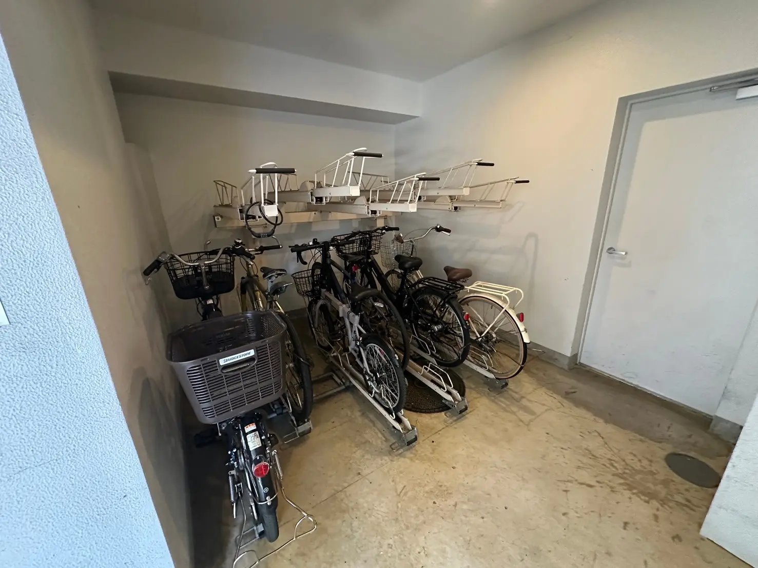 駐輪スペースに停められた自転車、壁掛け式の自転車ラック、コンクリートの床