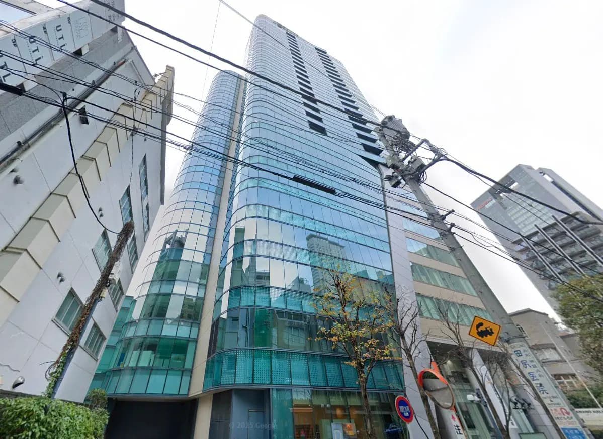 - 近代的なガラス張りのオフィスビル、周囲の建物や電線が見える街の風景