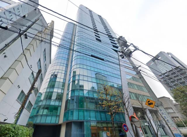 - 近代的なガラス張りのオフィスビル、周囲の建物や電線が見える街の風景
