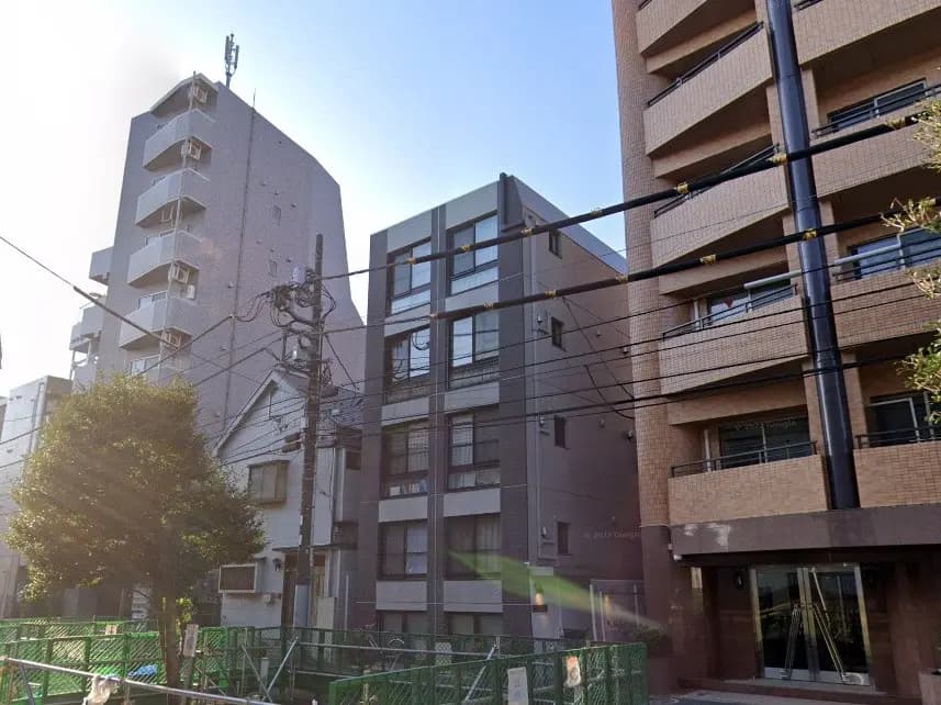 日本の都市部にある現代的なマンション群、晴れた日の青空と街路樹