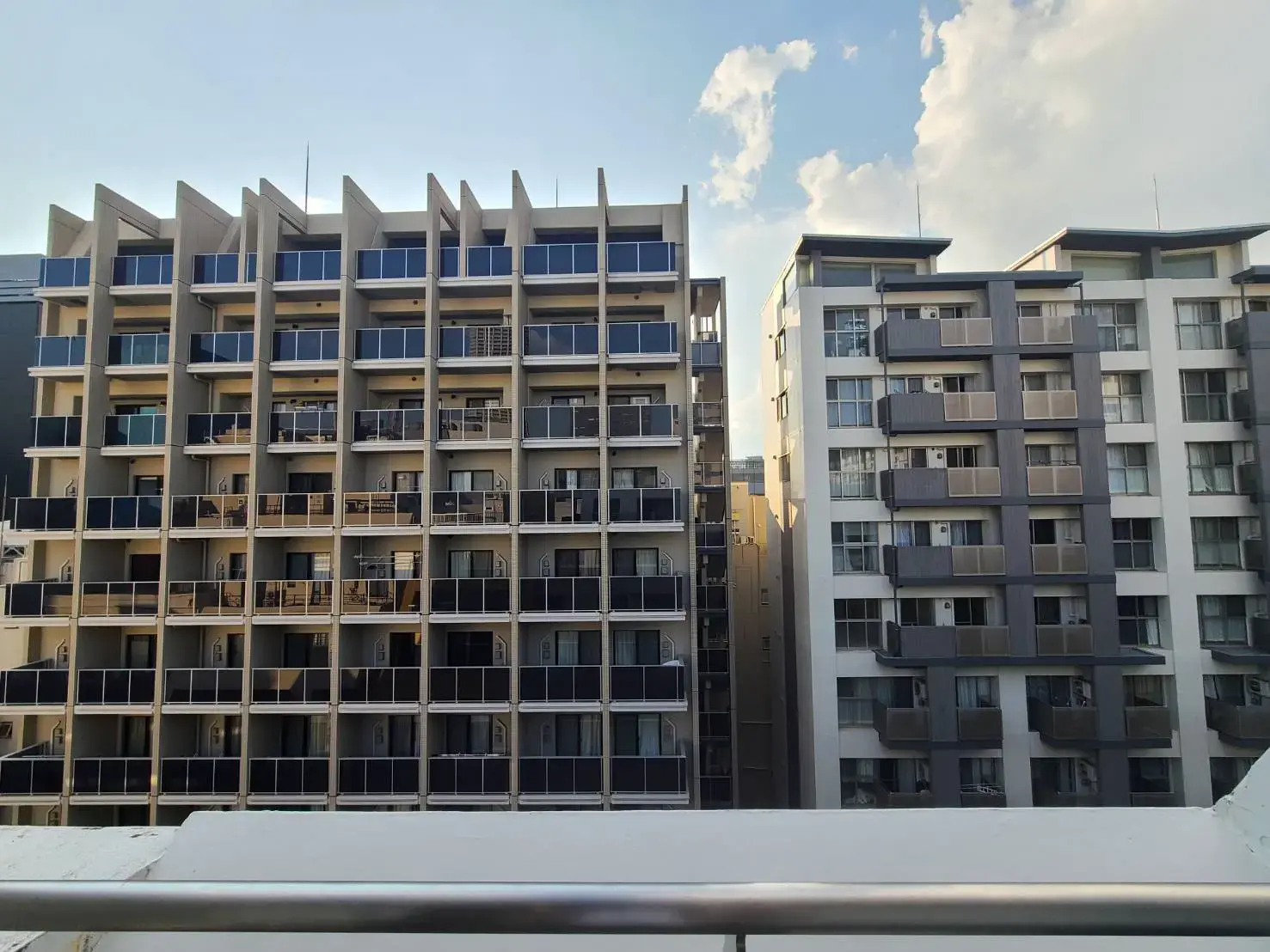 現代的なデザインのマンション外観、明るい日差しが差し込むバルコニー