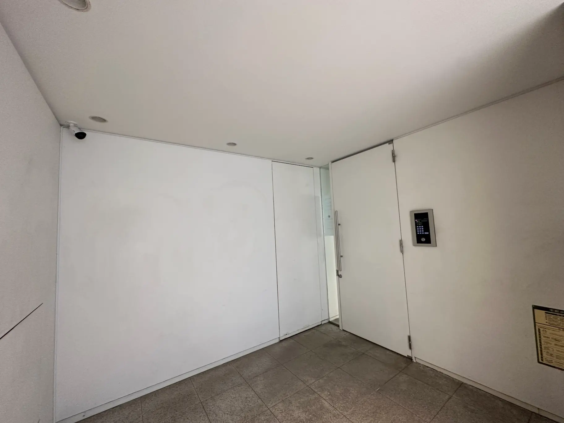 現代的なエントランスホール、白壁とタイルの床、インターホン設置