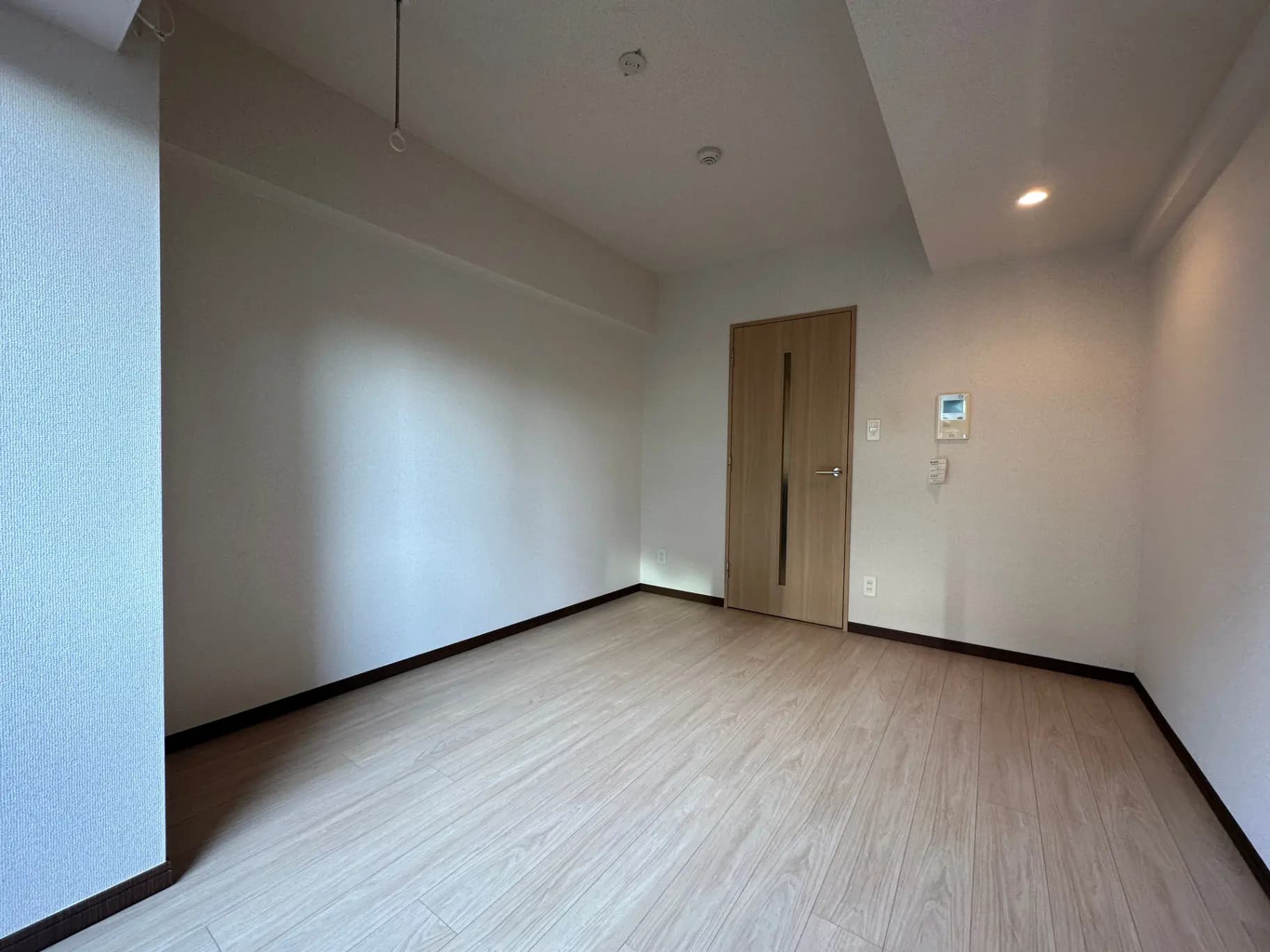 明るい室内の無垢フローリングが特徴的な新築マンションの空き部屋