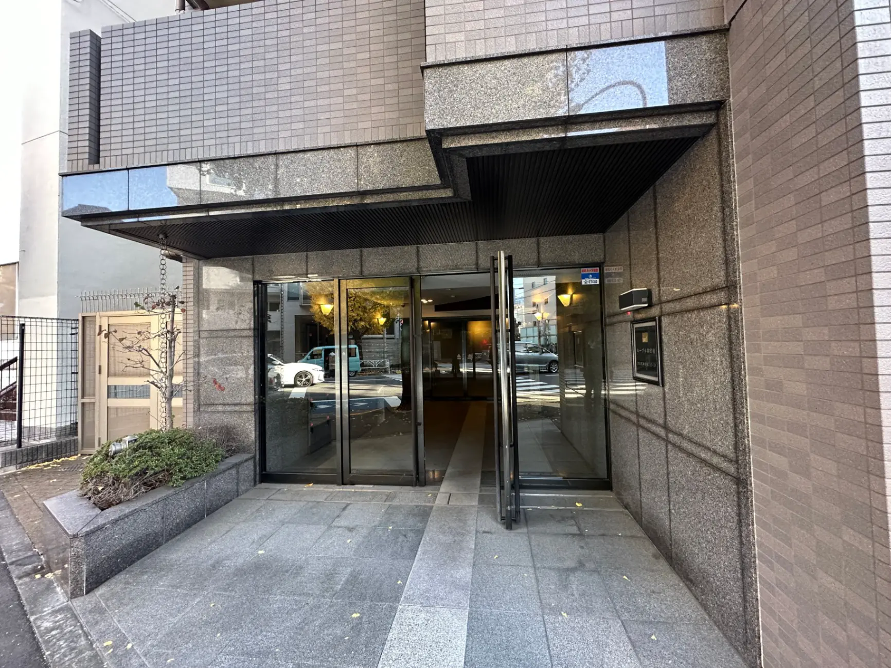 現代的な建築のオフィスビル入り口、ガラスドアと花崗岩の壁面デザイン