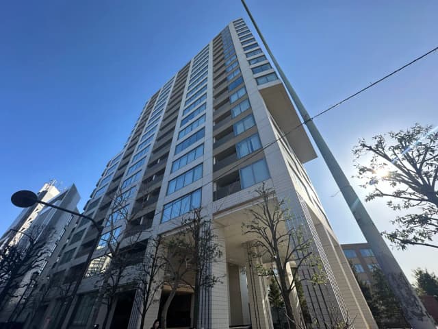 高層マンションの外観、青空と都市樹木の下でのモダンな建築スタイル