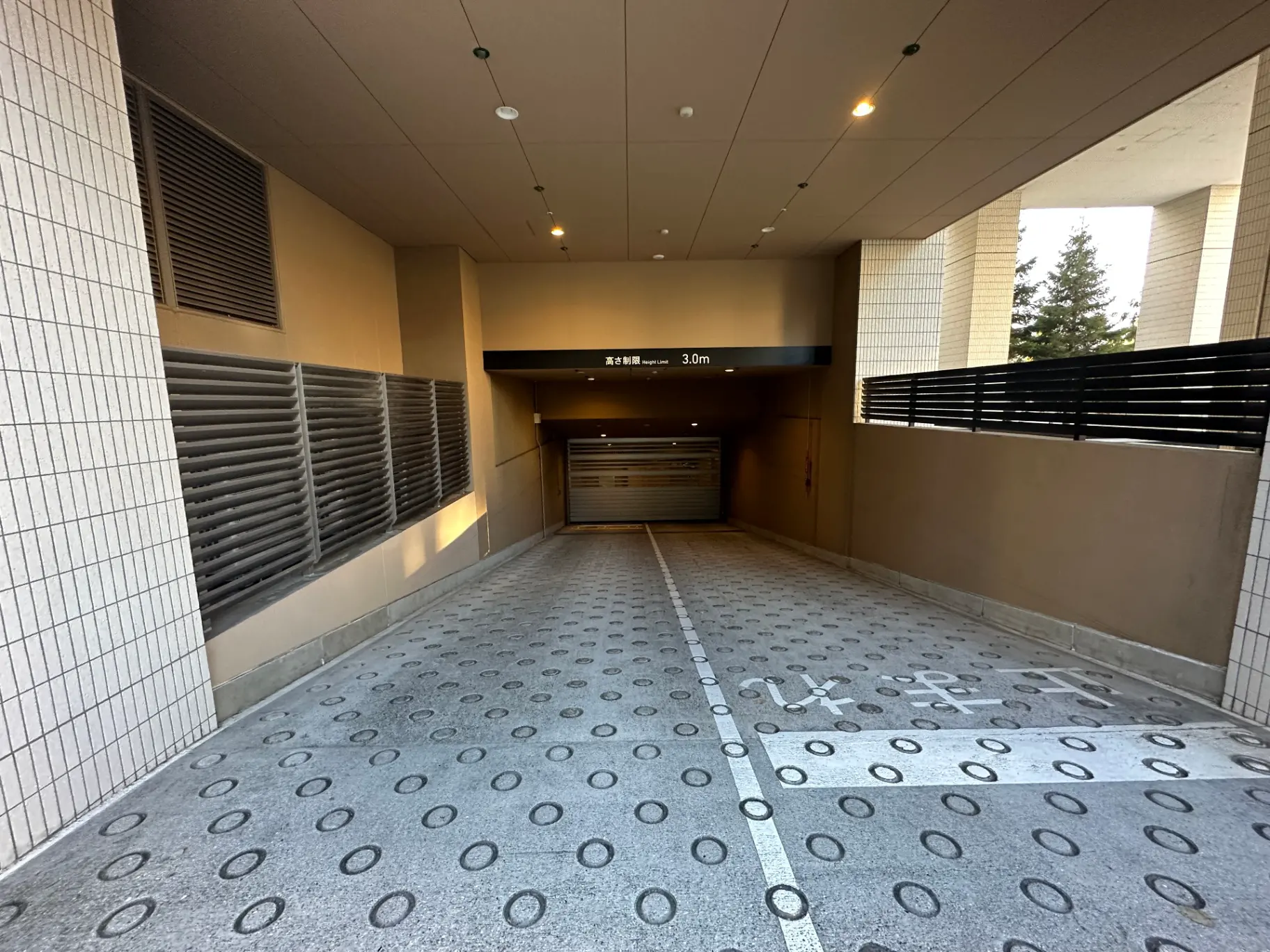 建物の入口にある駐車場へのスロープ、高さ制限3.0m、照明付きで安全な通路