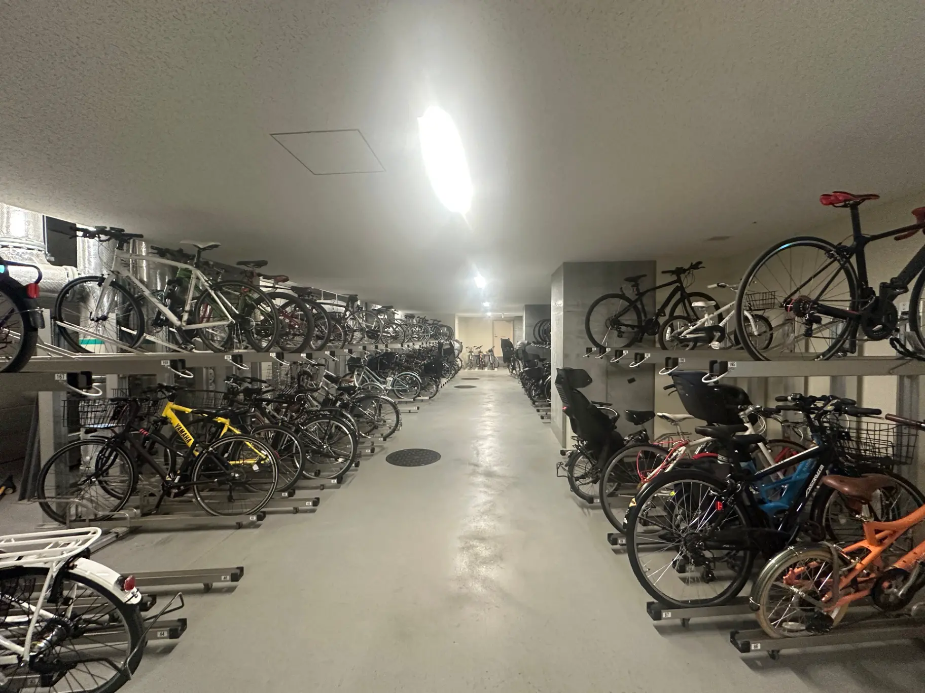 多種多様な自転車が整然と並べられた駐輪場、明るい照明が施され安全な保管スペース