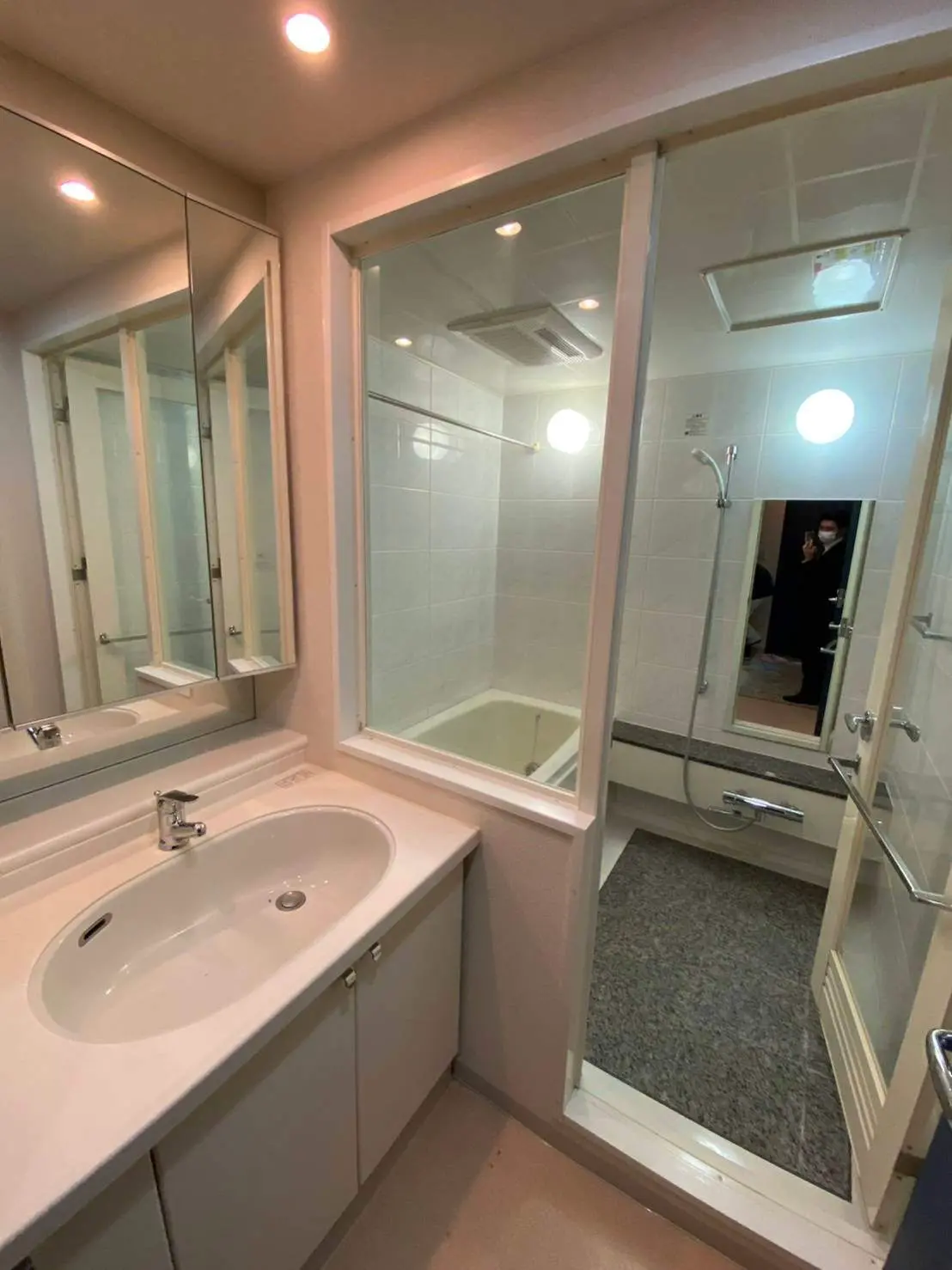 照明と大鏡のある清潔感のあるバスルーム、シャワーキャビンと広い洗面台のインテリア