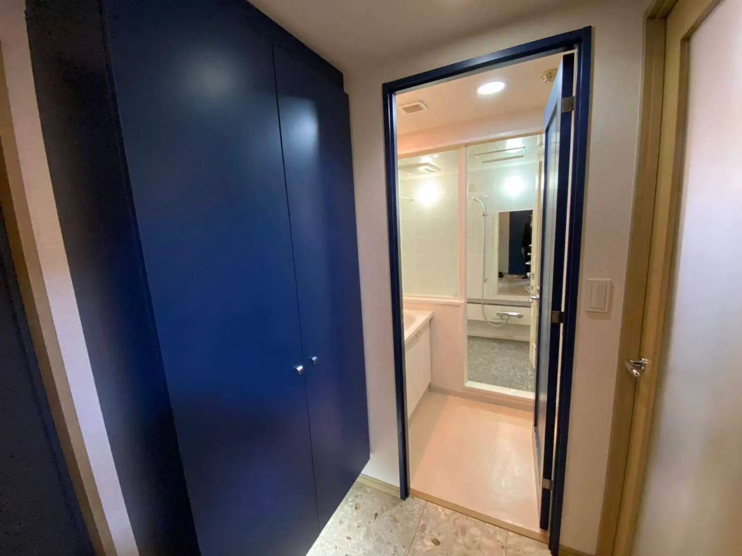 モダンな住宅のバスルーム入口、開いたドア、内側は明るい照明と清潔感のあるインテリア