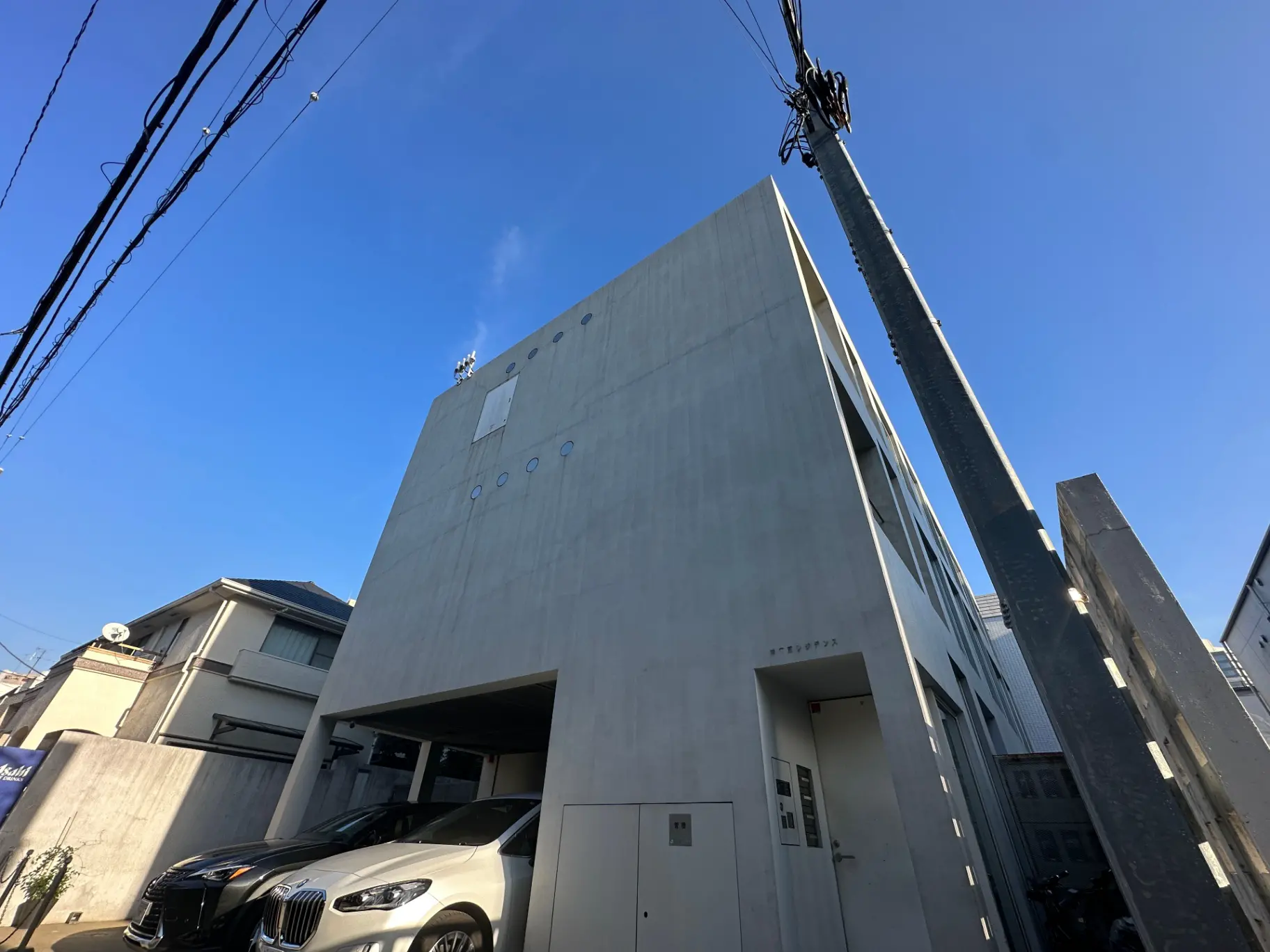 モダンな建築デザインの都市住宅、コンクリートの外壁、青空と電線が交差する景観