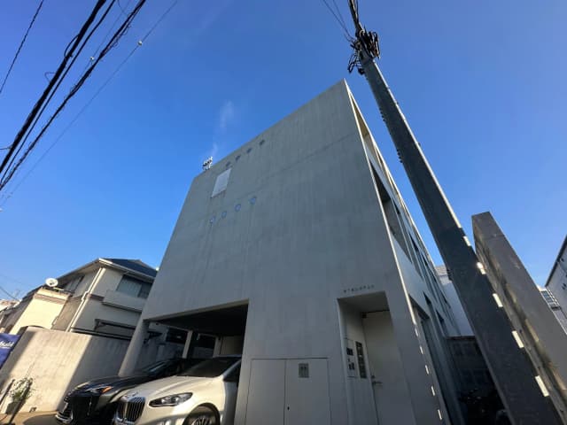 モダンな建築デザインの都市住宅、コンクリートの外壁、青空と電線が交差する景観