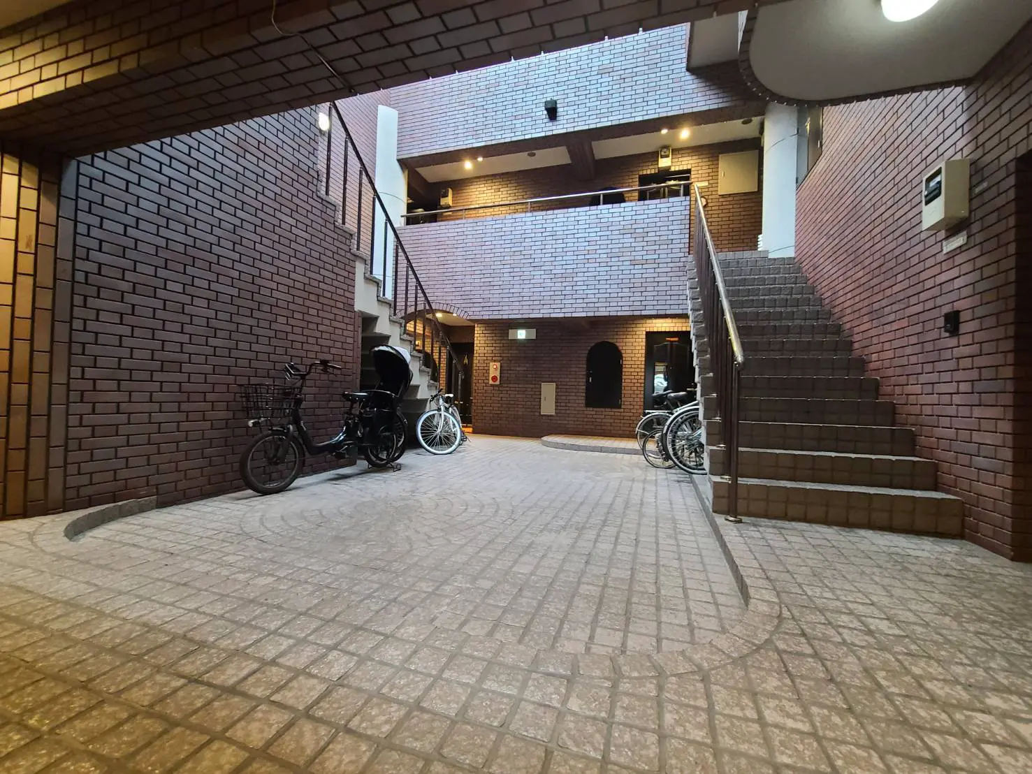 レンガ造りのアーチと階段が特徴的な屋外共有スペース、自転車駐輪エリア
