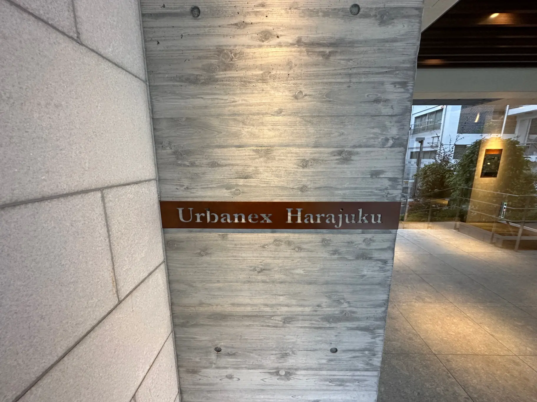 木目調の壁に「Urbanex Harajuku」と書かれた看板があるエントランス