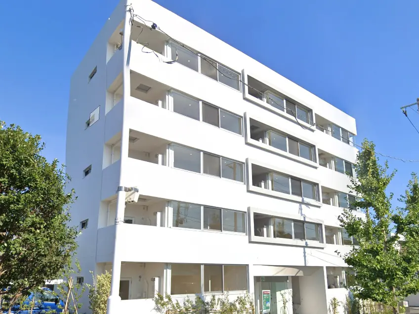 - 白い外観の建物、広い窓と外の緑が印象的な現代的なアパートメントのファサード